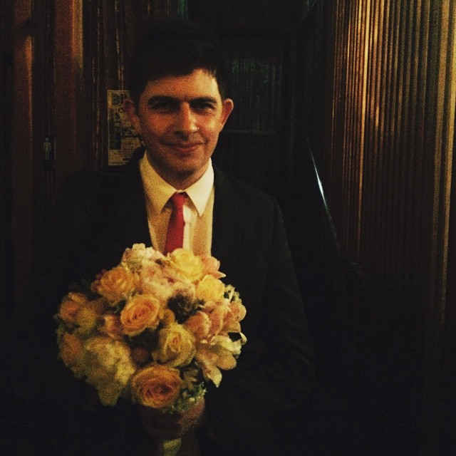 a man wearing a suit and tie holding a bouquet of flowers