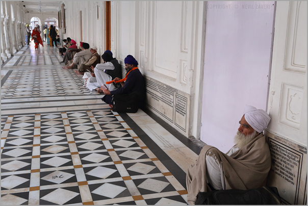 group of men sit on a long wall by the door