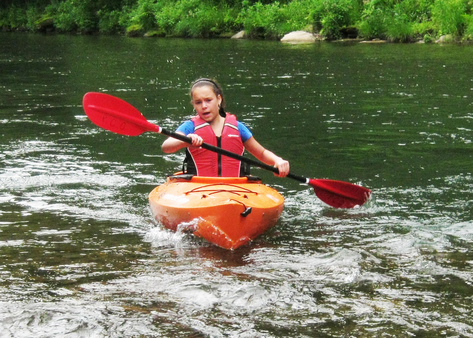 a person kayaking in water near a lush green hillside