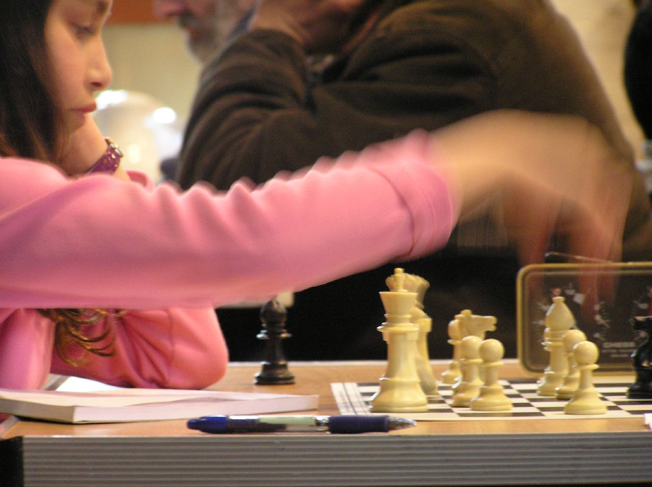 a girl playing chess with an adult