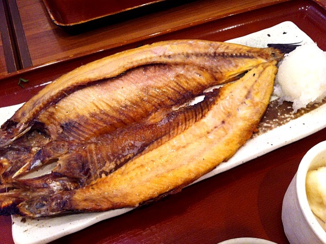 a large fish is on a  board near some other dishes