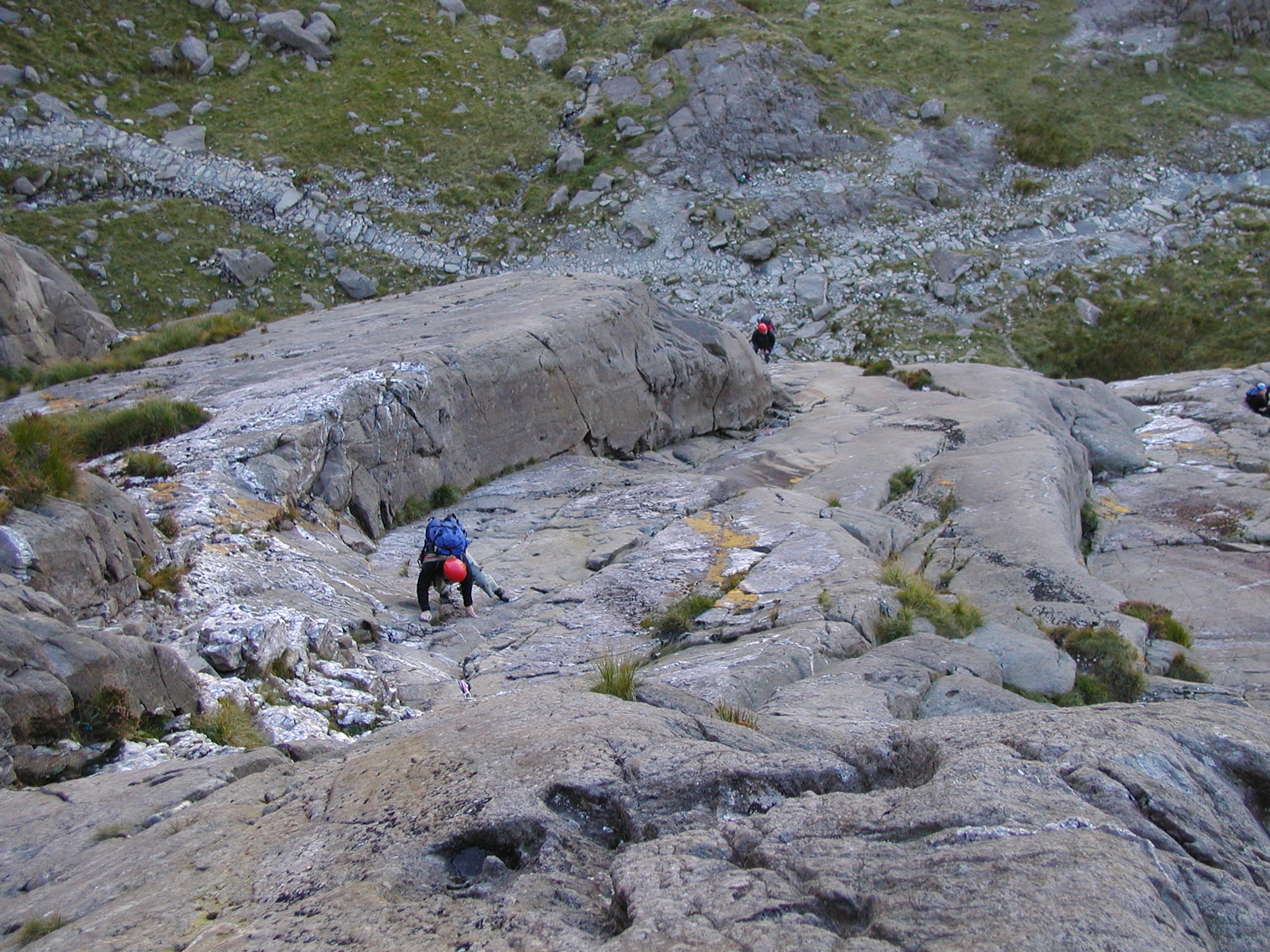 some hikers on rocks walking up the side of a mountain