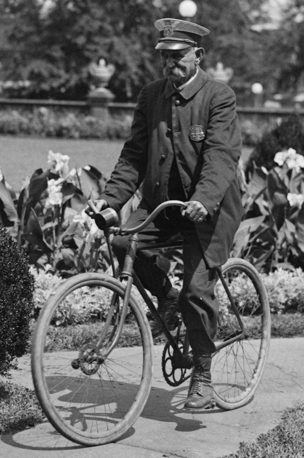 an old black and white pograph of a man on a bicycle
