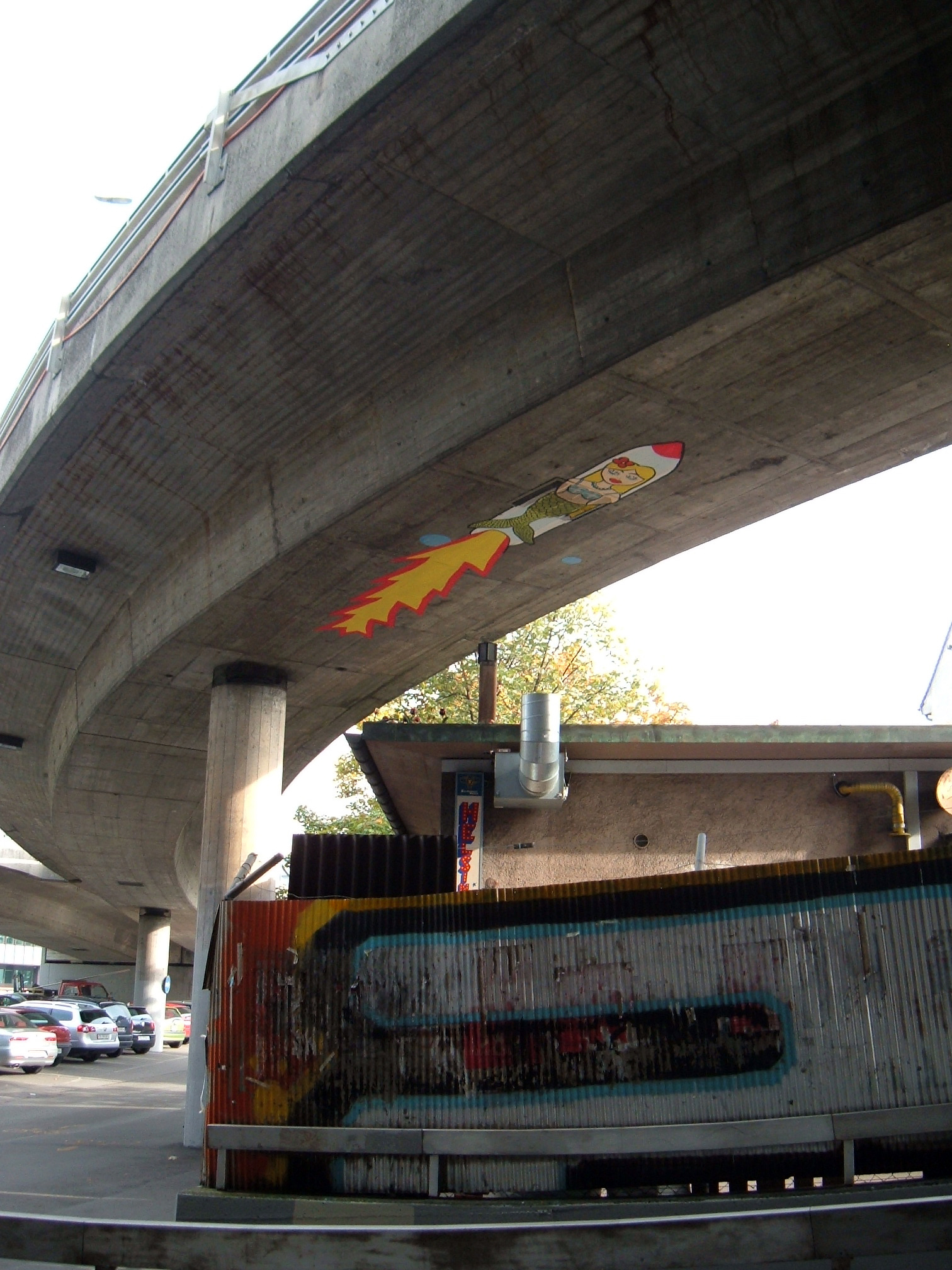 the side of a street with some graffiti under a bridge