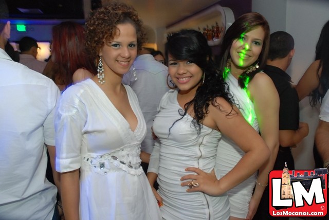 three women pose together at a party in white outfits