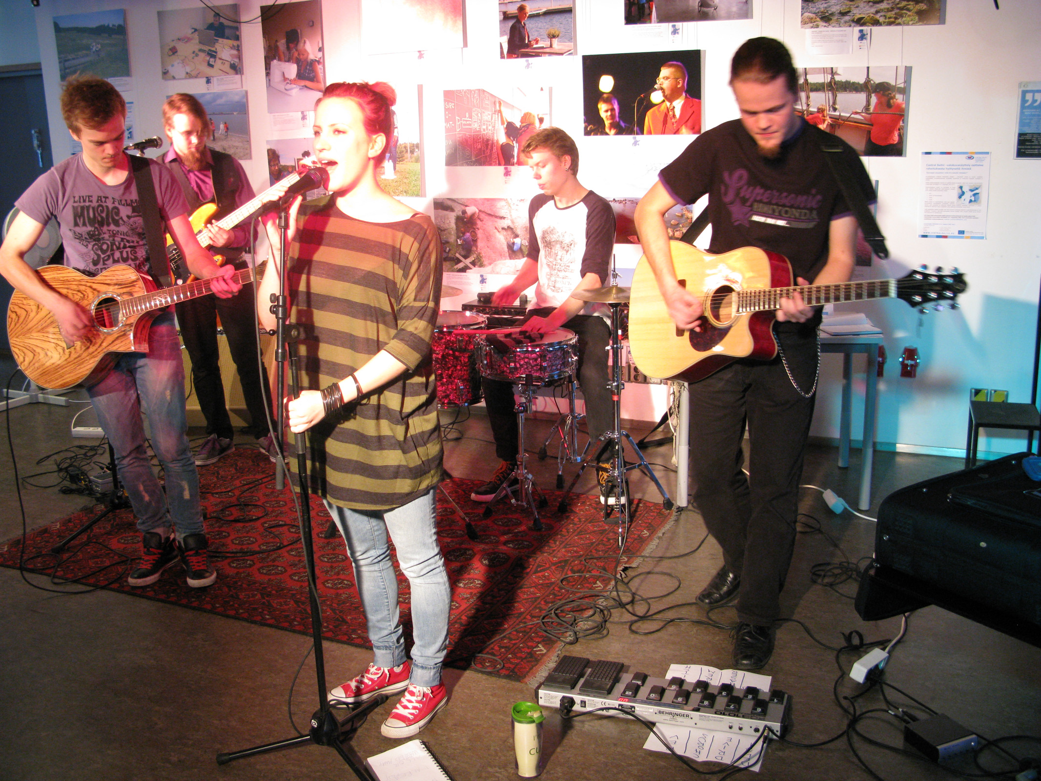 a man singing with other young men playing guitars and singing in the background