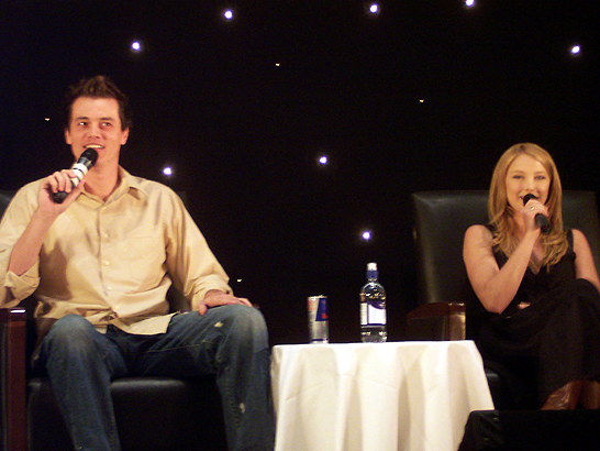 the two people are sitting on chairs in front of a microphone