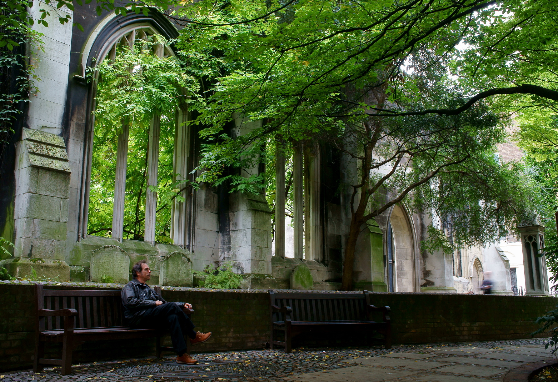a man is sitting on a bench at an abandoned building