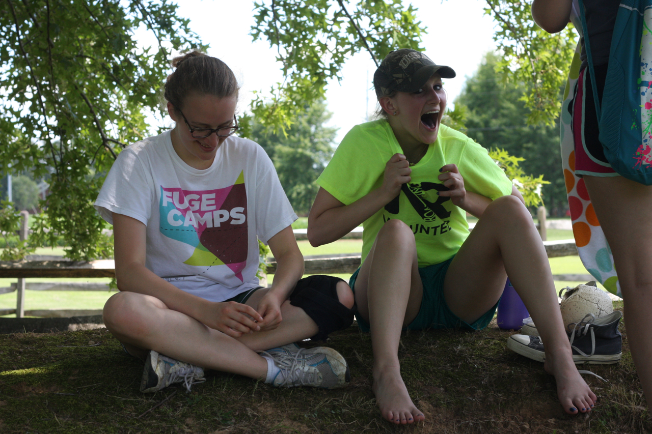 two women sitting next to each other in the grass