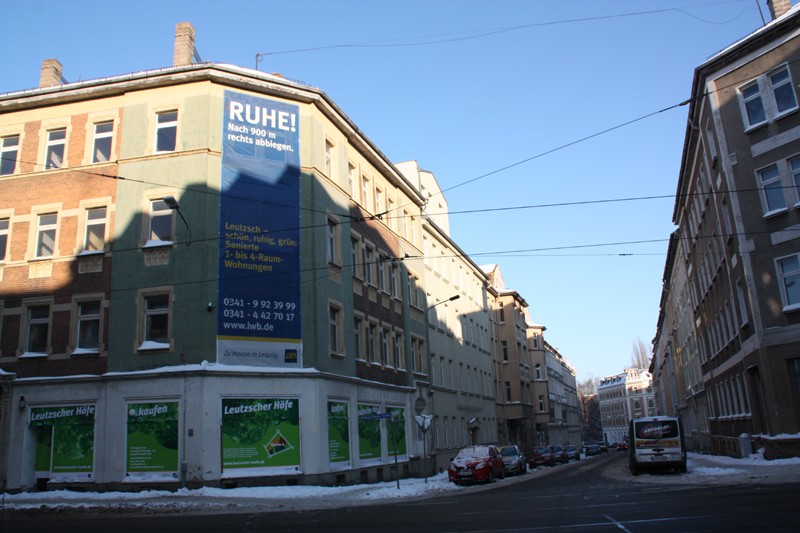 large blue sign in front of buildings on a corner
