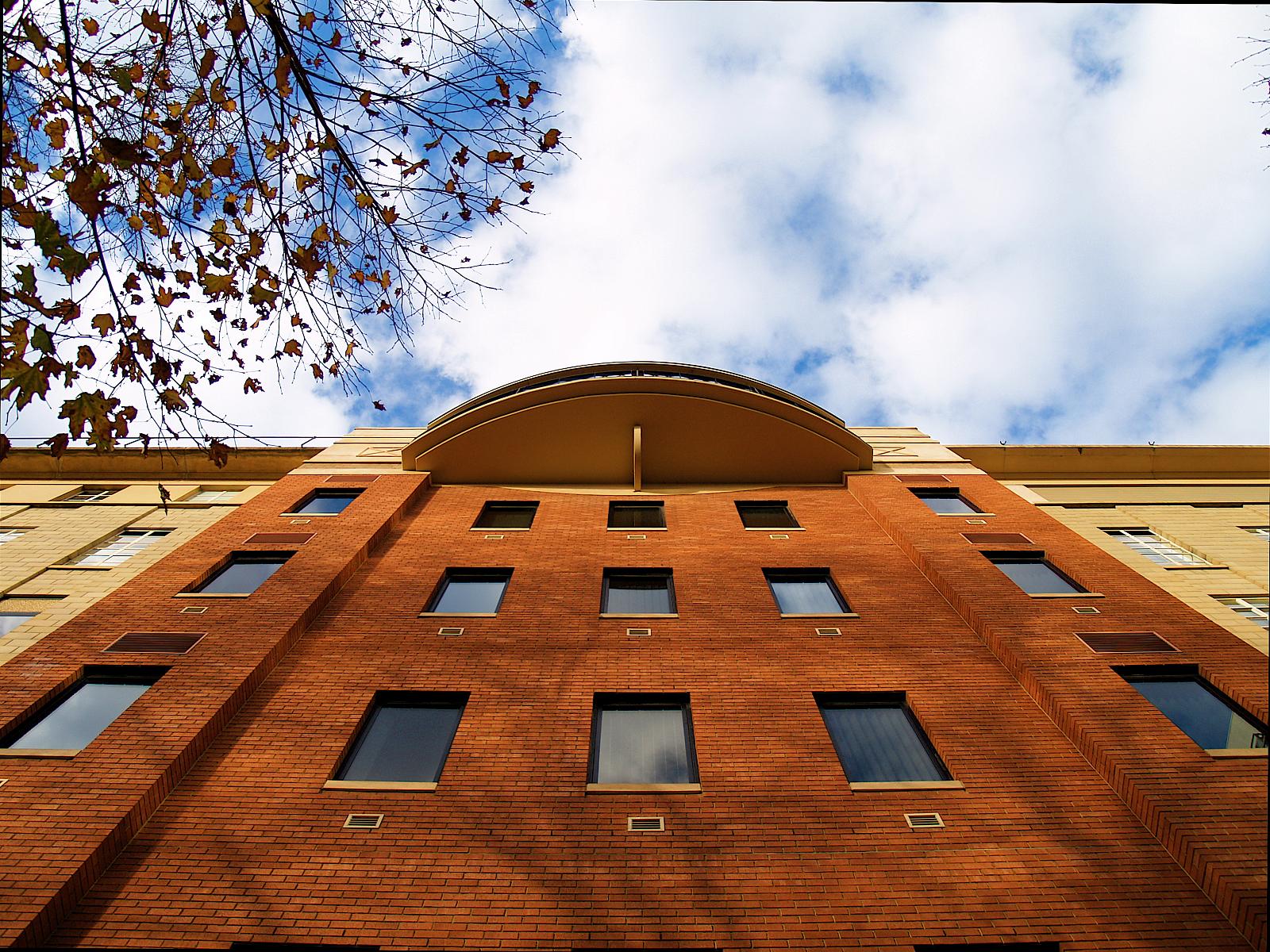 a tall brick building with a white roof under a cloudy blue sky