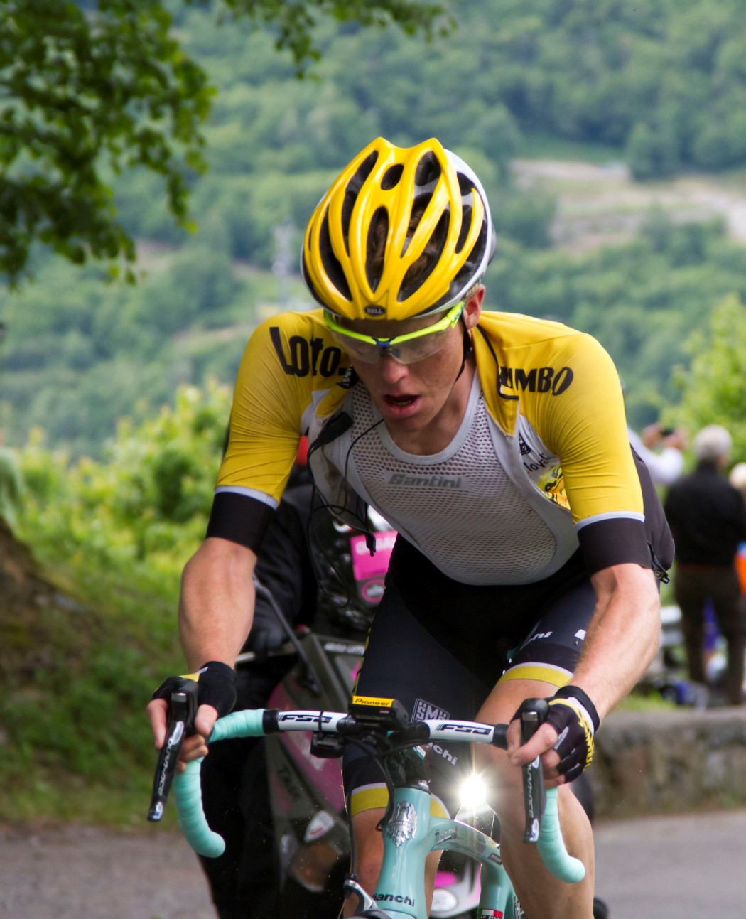 a male in a bike racing uniform with other cyclists on a road