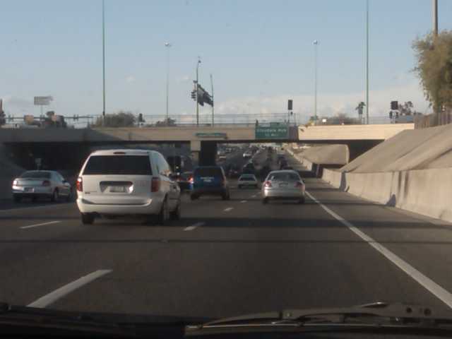 two lane highway with cars travelling under a bridge