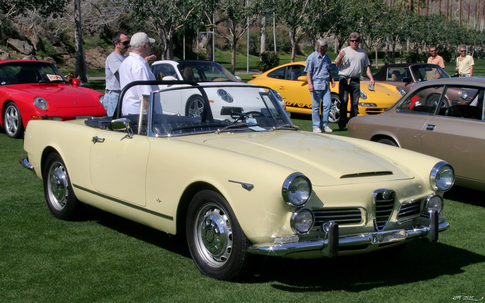 two men are standing in front of two classic cars