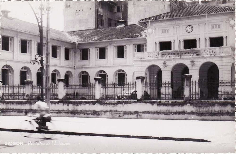 a man rides a motorcycle in front of two large building