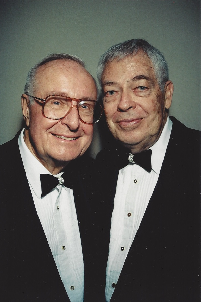 two older men wearing tuxedos standing together