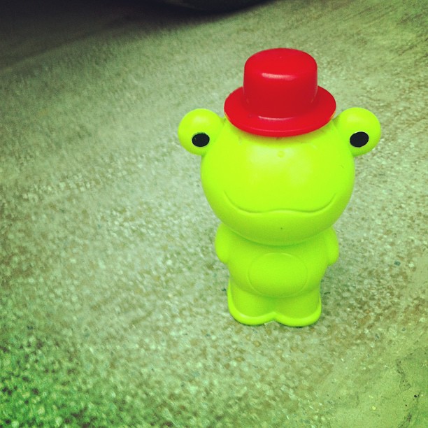 a plastic green toy that has a red hat on it