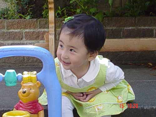 a child posing for a picture in front of a playground play set