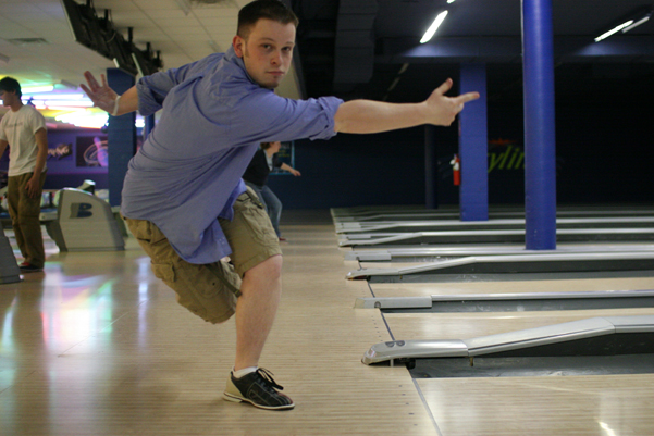 a young man skateboards down an indoor bowling alley