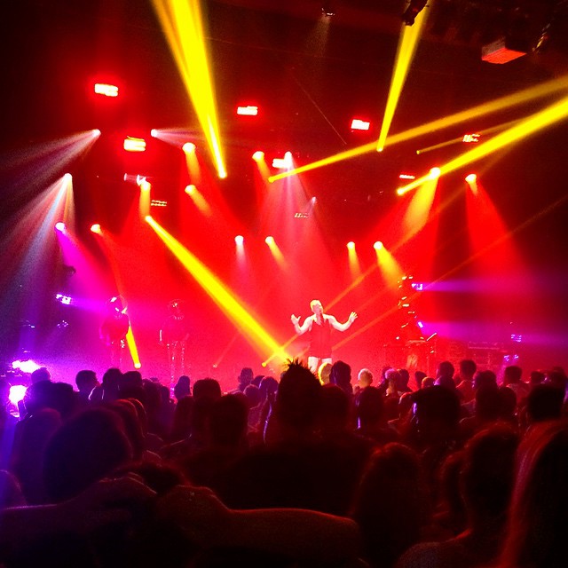 many people at a concert are illuminated by different colored lights