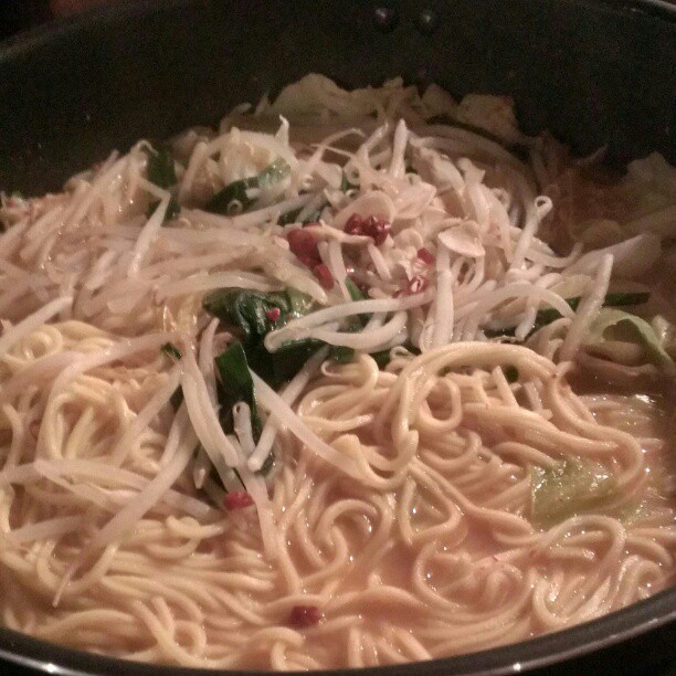 a bowl filled with noodles and cheese next to green peppers