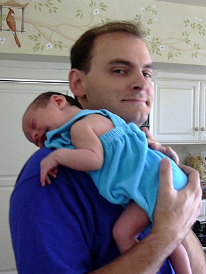 man holding child in kitchen with white cupboards
