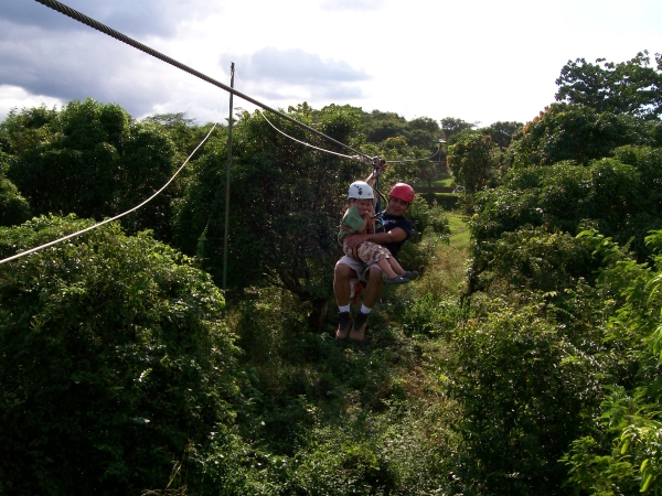 an older man and a  on a zip line over the forest