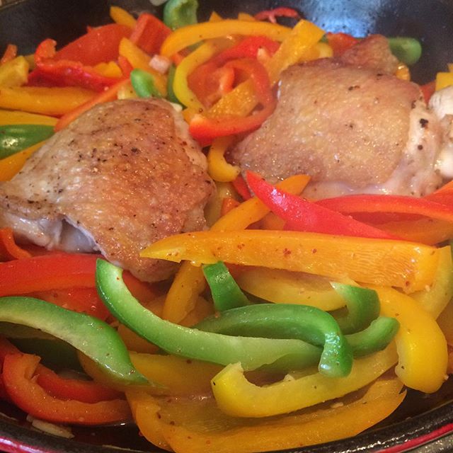 a pan with meat, bell peppers and onions