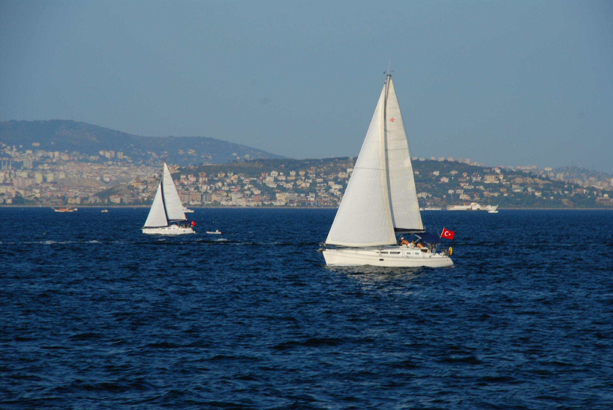 two sailboats float in the middle of a large blue body of water