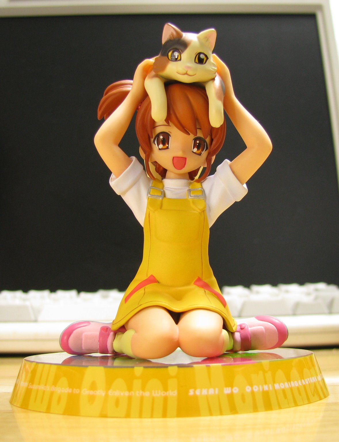 a cute doll sitting on top of a laptop computer