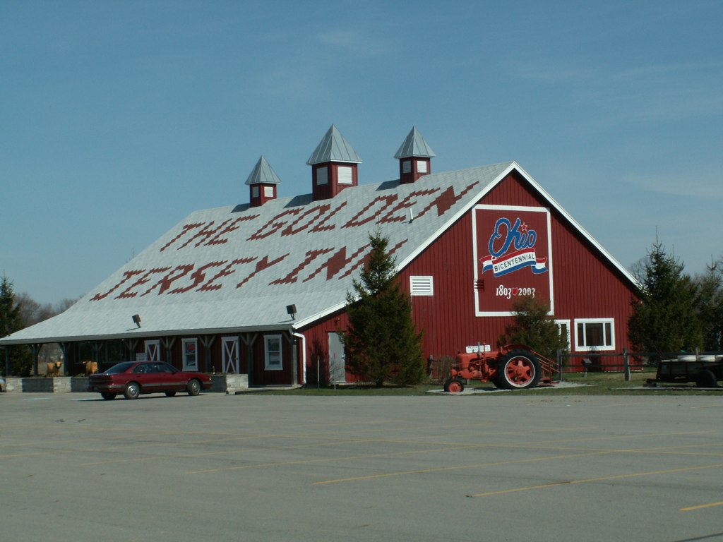 a large barn is made of red wood and is next to trees