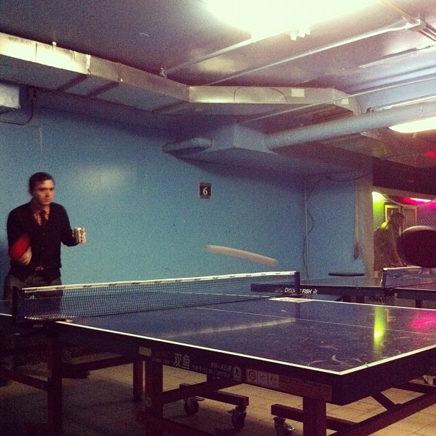 a man playing ping pong in an indoor tennis court