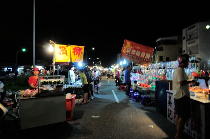 a street at night with some vendors standing in line