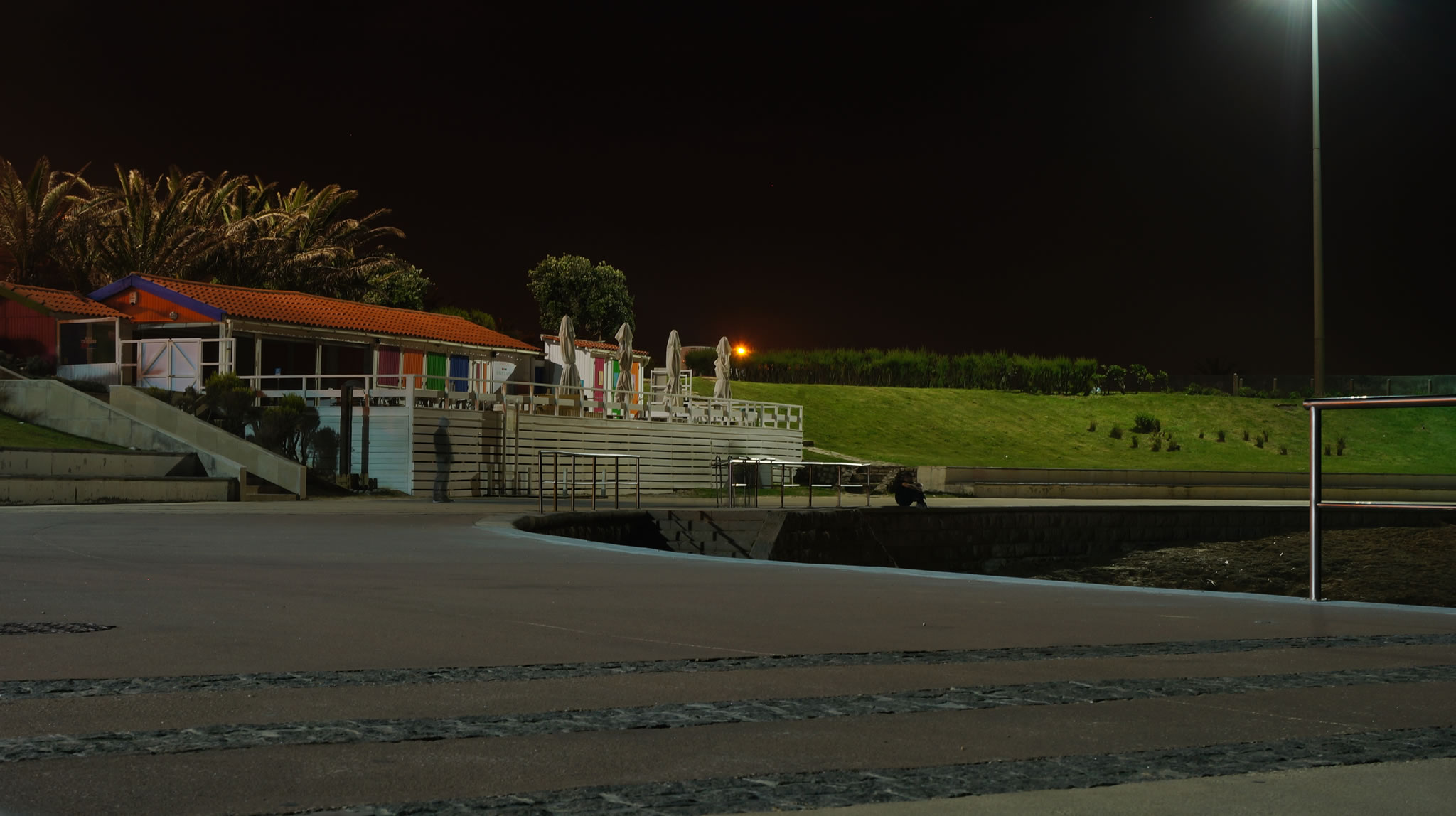 a park area at night with stairs, grassy hills and lights