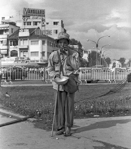 an old man stands near the water and holds a cane