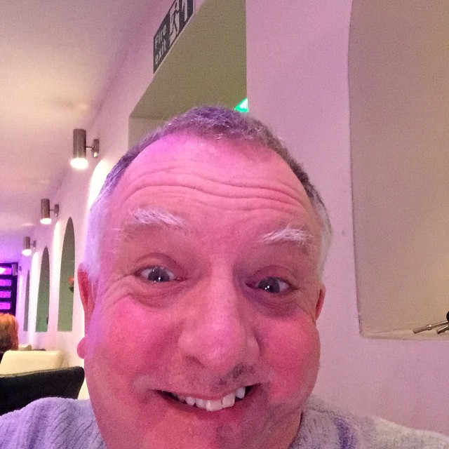 a man with shaved hair sitting at a table