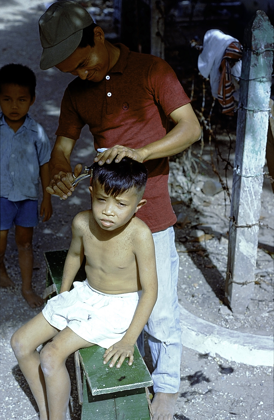 a boy getting his hair comb by an old barber