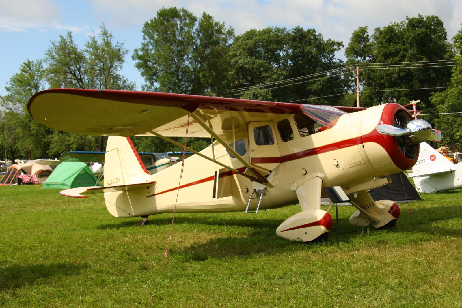 an old style airplane sits in the middle of some grass