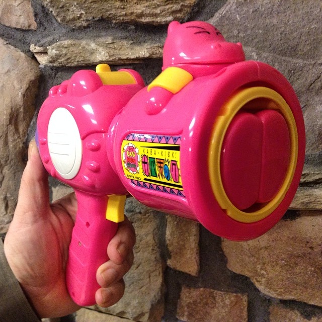 a pink and yellow toy gun being held by a hand
