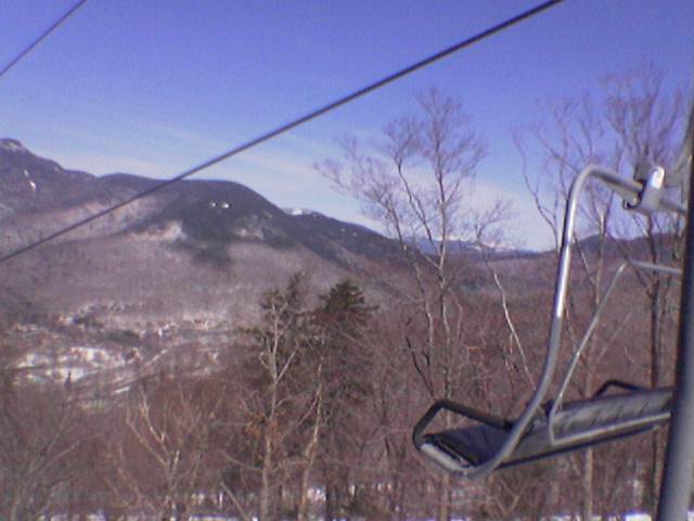 ski lift with skiers riding down it in the mountains