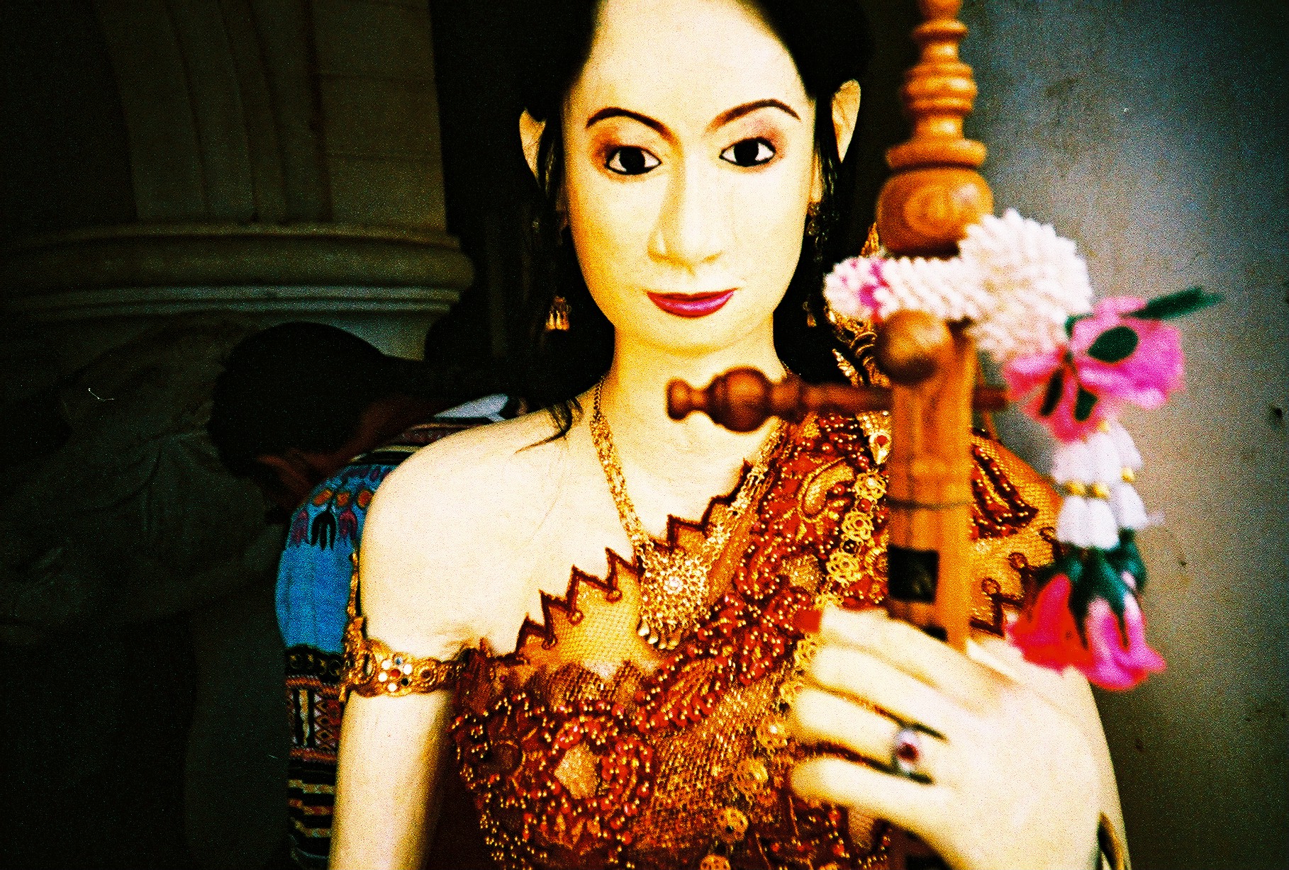 a statue holding a wooden object with large eyes