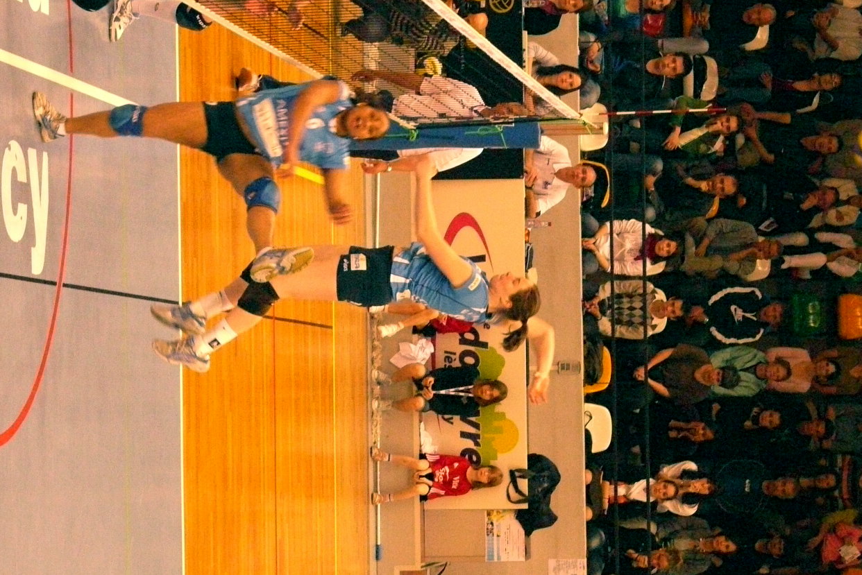 two female volleyball players compete during an indoor match