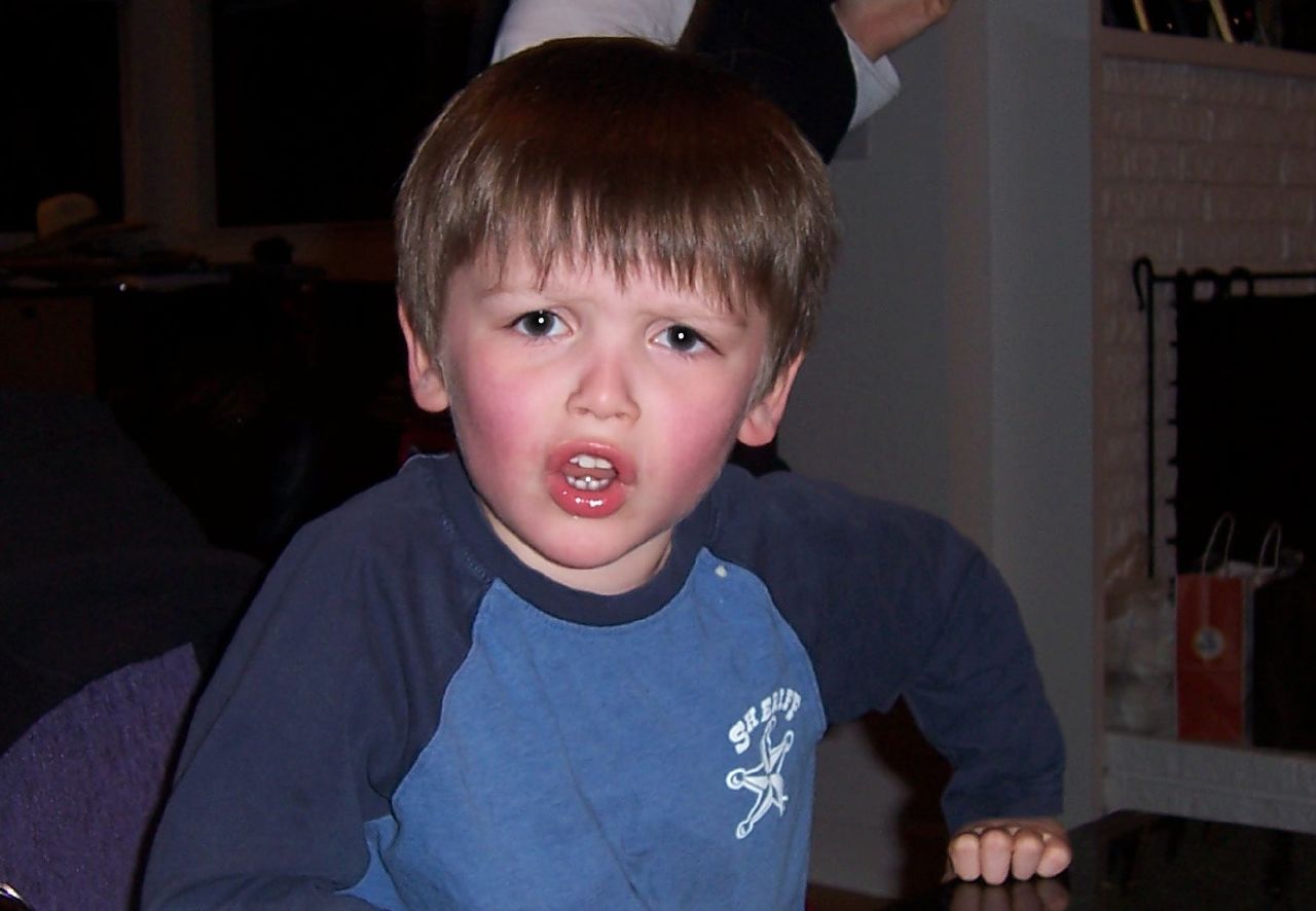 a boy is sitting at the table, playing with his toy