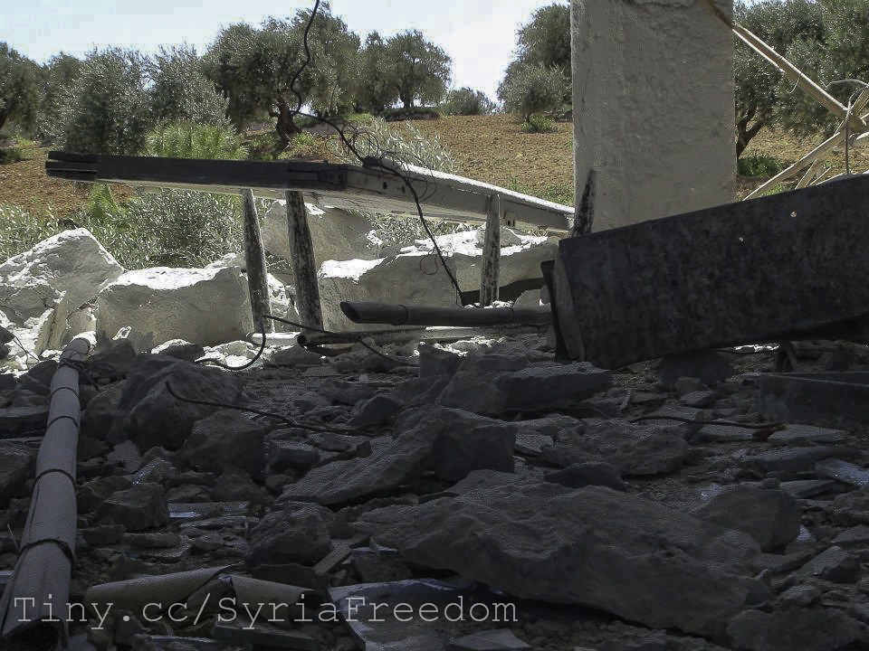 a broken and destroyed gas station near an olive grove