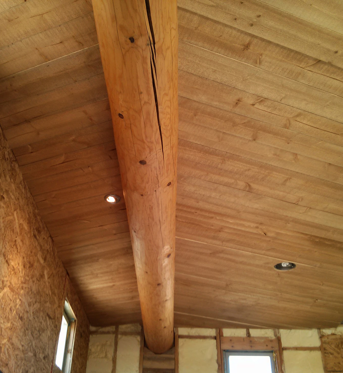 an unfinished wooden ceiling and some windows in an empty room