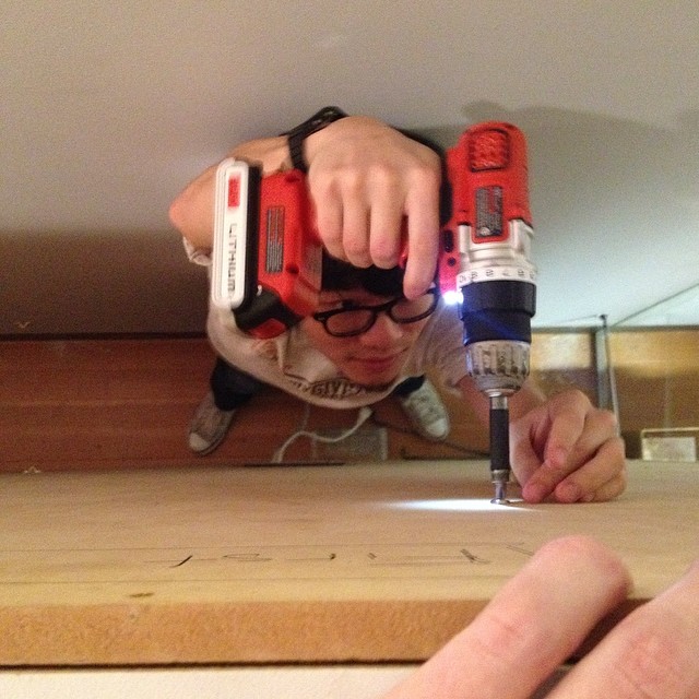 man holding an electric drill to drill a plank