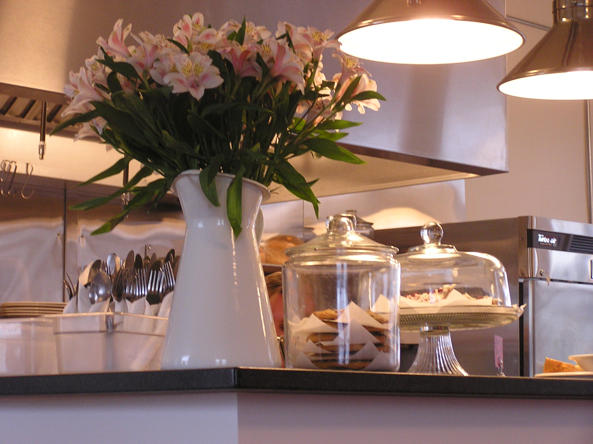 pink flowers are in a vase and some silver wares