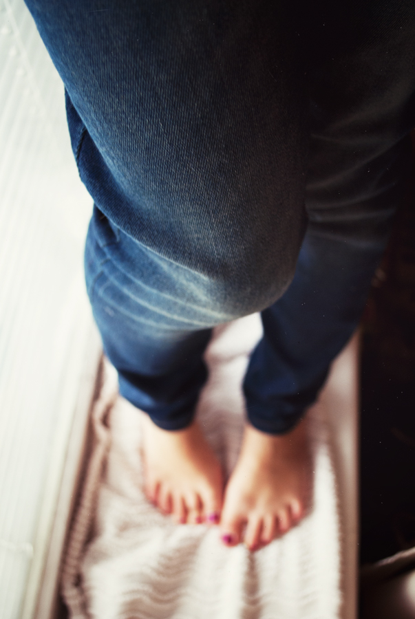 a person stands on the bed with their feet up