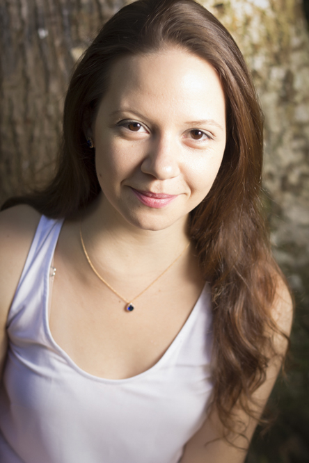 a woman standing next to a tree posing for the camera