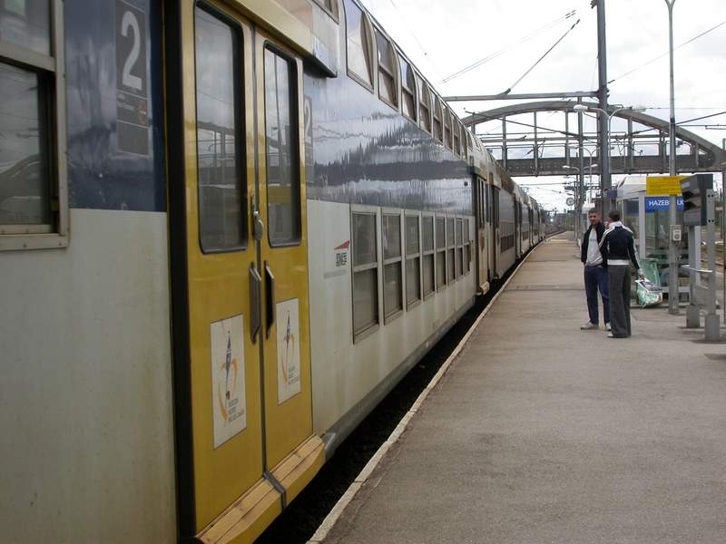 two men are walking next to a large yellow train
